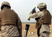 A Marine drop a explosive round into a mortar tube.