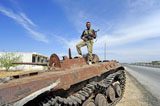 ACH100477M
Member of the Free Syrian Army stands on top of a demolished tank.