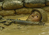 STK100476M
U.S. Navy soldier crawls through mud-filled trenches as part of an obstacle course.