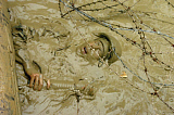 STK100883M
A Seabee emerges from muddy water under razor and barbed wire.