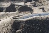 STK101896M
A static display of an ordnance shell and a mine lay half-buried in the sand.