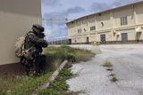 STK102156M
A Marine posts security as a team of Marines prepare to enter an enemy warehouse.