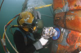 STK102231M
U.S. Navy Diver uses a grinder to file down a repair patch on the submerged bow of the USS Ogden.