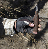 STK102503M
An engineer displays a bullet found near a weapons cache.