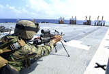 STK103097M
A U.S. Marine adjusting his weapon on the flight deck of USS Harpers Ferry.
