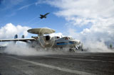 STK106728M
An F/A-18C Hornet flies overhead as an E-2C Hawkeye prepares to launch.