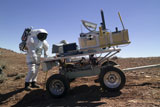 STK201832S
An astronaut equipped with a Mark-III suit, pauses at the rear of a science trailer.