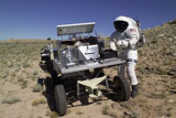 STK201833S
An astronaut equipped with a Mark-III suit operates the controls for a robot