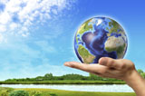VET200044S
Human hand holding Earth globe with a green landscape background.