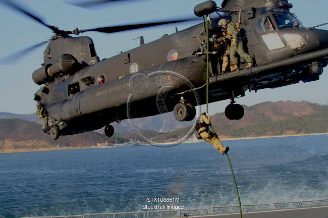 A U.S. Navy SEAL fast-ropes from a MH-47 Chinook helicopter ...