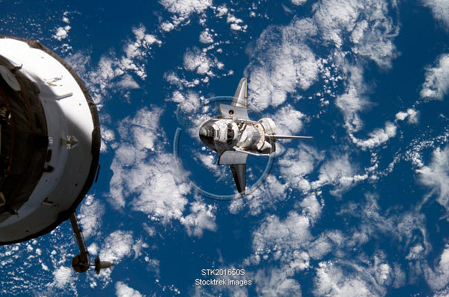 Space Shuttle Discovery backdropped by a blue and white Earth ...