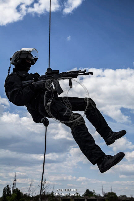 Special forces operator during assault rappelling with weapons ...