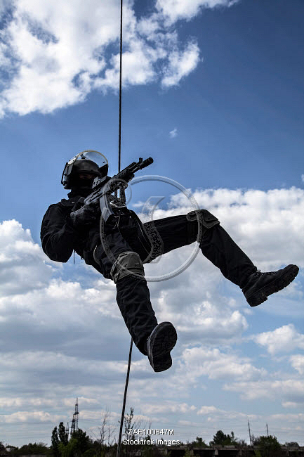 Special forces operator during assault rappelling with weapons ...
