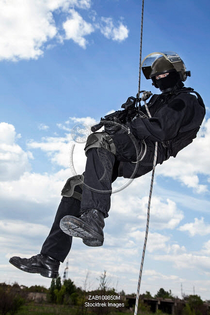 Special forces operator during assault rappelling with weapons ...