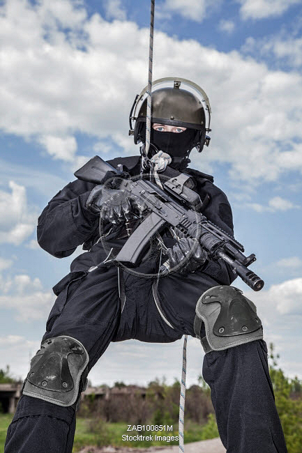 Special forces operator during assault rappelling with weapons ...